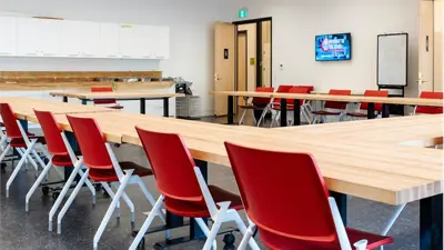 Large room with tables and red chairs, class room style