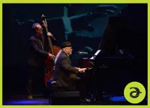 Man sitting at a piano and another standing with an upright base