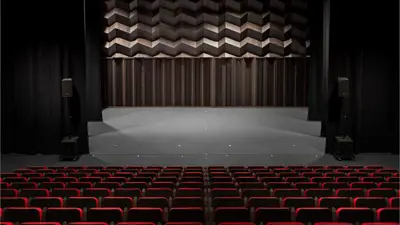 Performance hall with red seating and stage on the ground