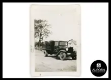Very old black and white picture of an old truck on a dirt road